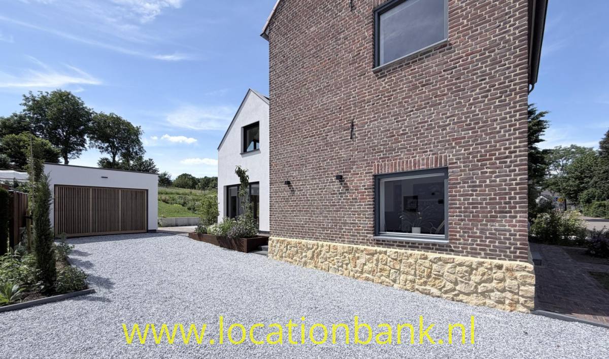 Backsteinhaus mit einem Natursteinsockel, einer Kiesauffahrt und einer freistehenden Garage.