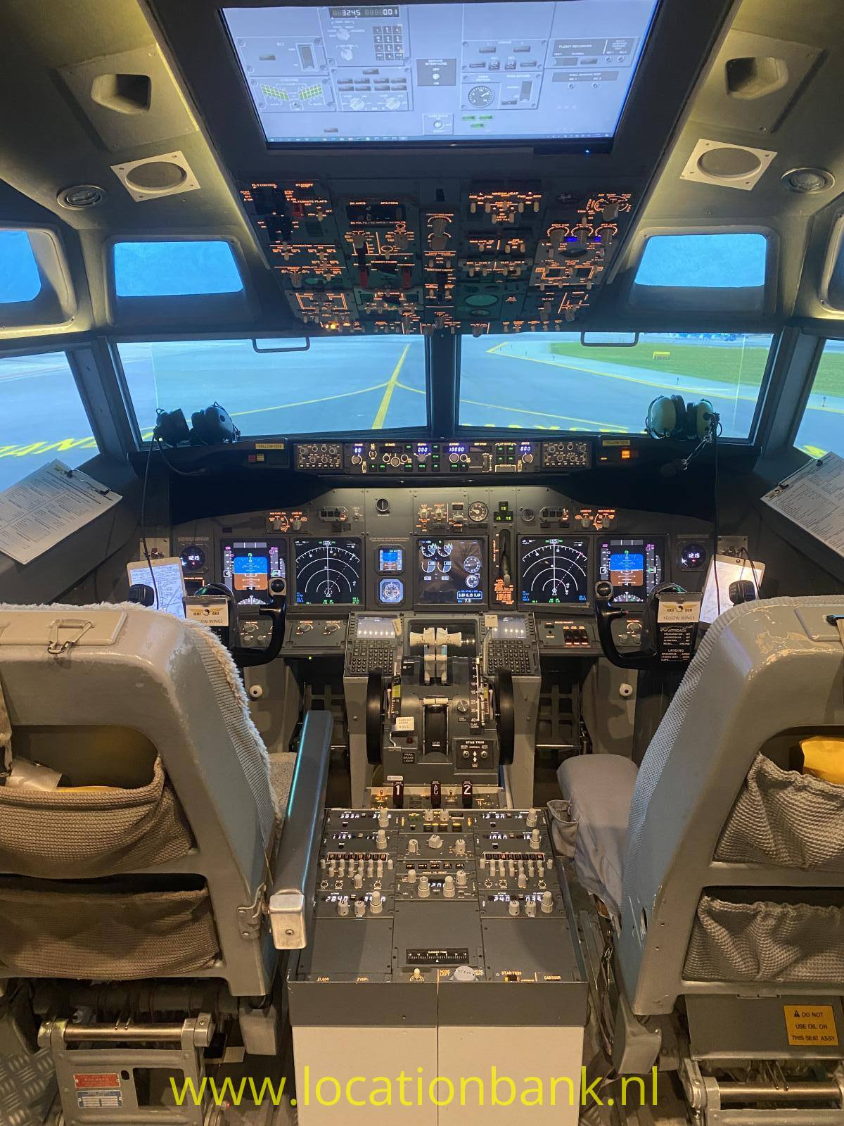 Das Cockpit zeigt zwei Pilotensitze, beleuchtete Bedienfelder und gelbe Markierungen auf dem Boden von Landungs Bahn vor der Frontscheibe.