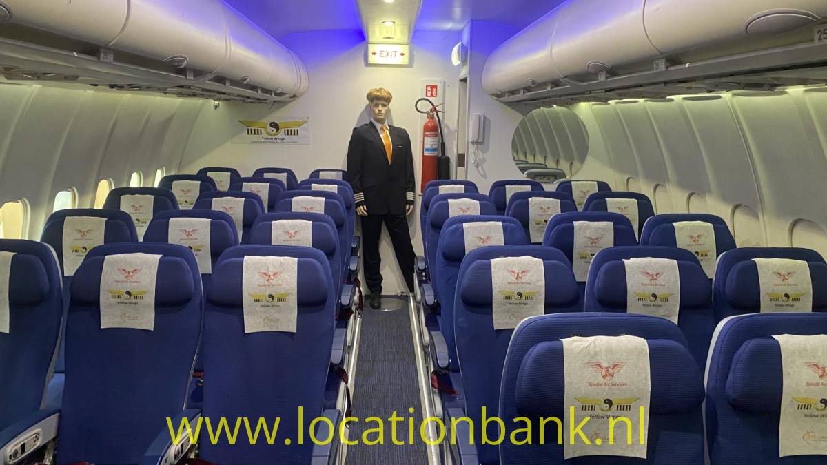 Ein Flugbegleiter steht im Gang zwischen Reihen blauer Sitze im Flugzeug.