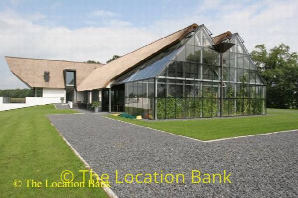 filmlocatie Moderne villa met veel glas, rieten dak, prive zwembad en mooie planten kas en carport
