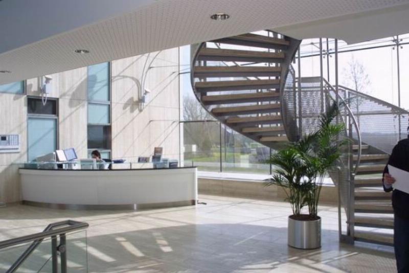 Modern office with a designer counter and a view at a staircase and big empty spaces.