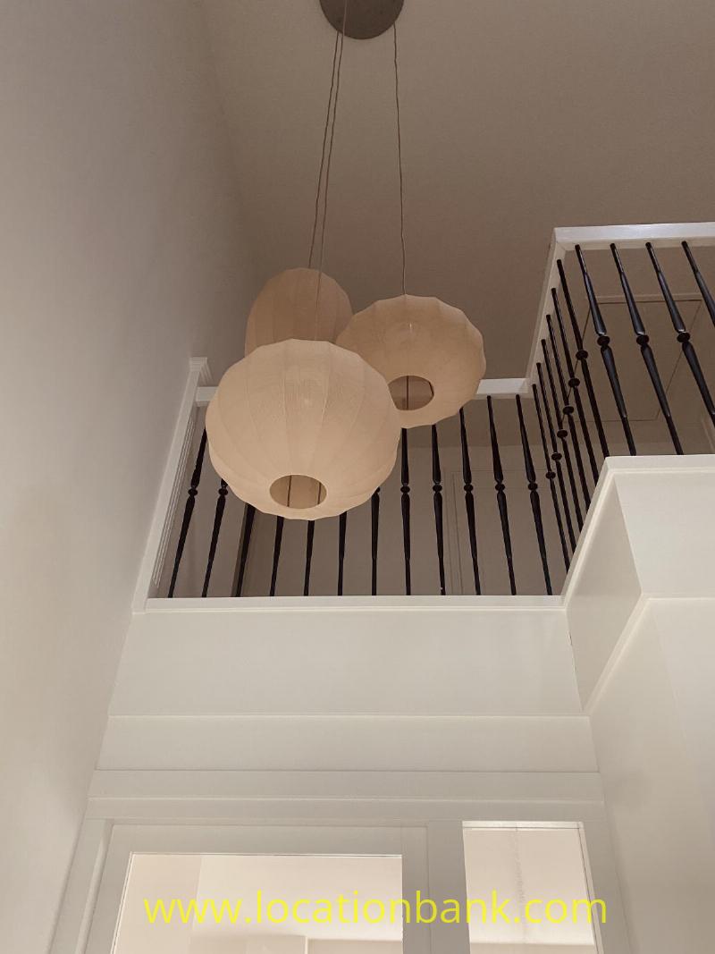 Round pendant lights hang above a white staircase with dark vertical balusters.