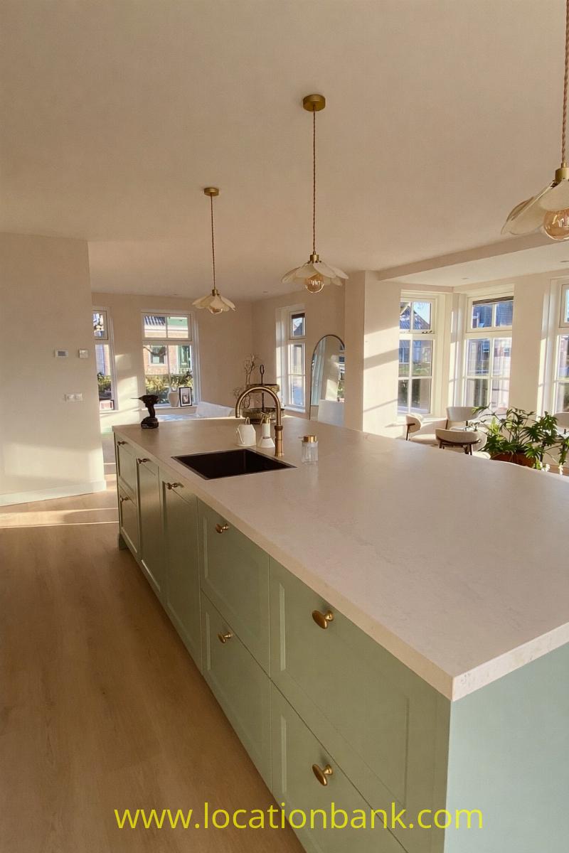 A large kitchen island with pale green cabinets and a white worktop stands at the centre of this kitchen.