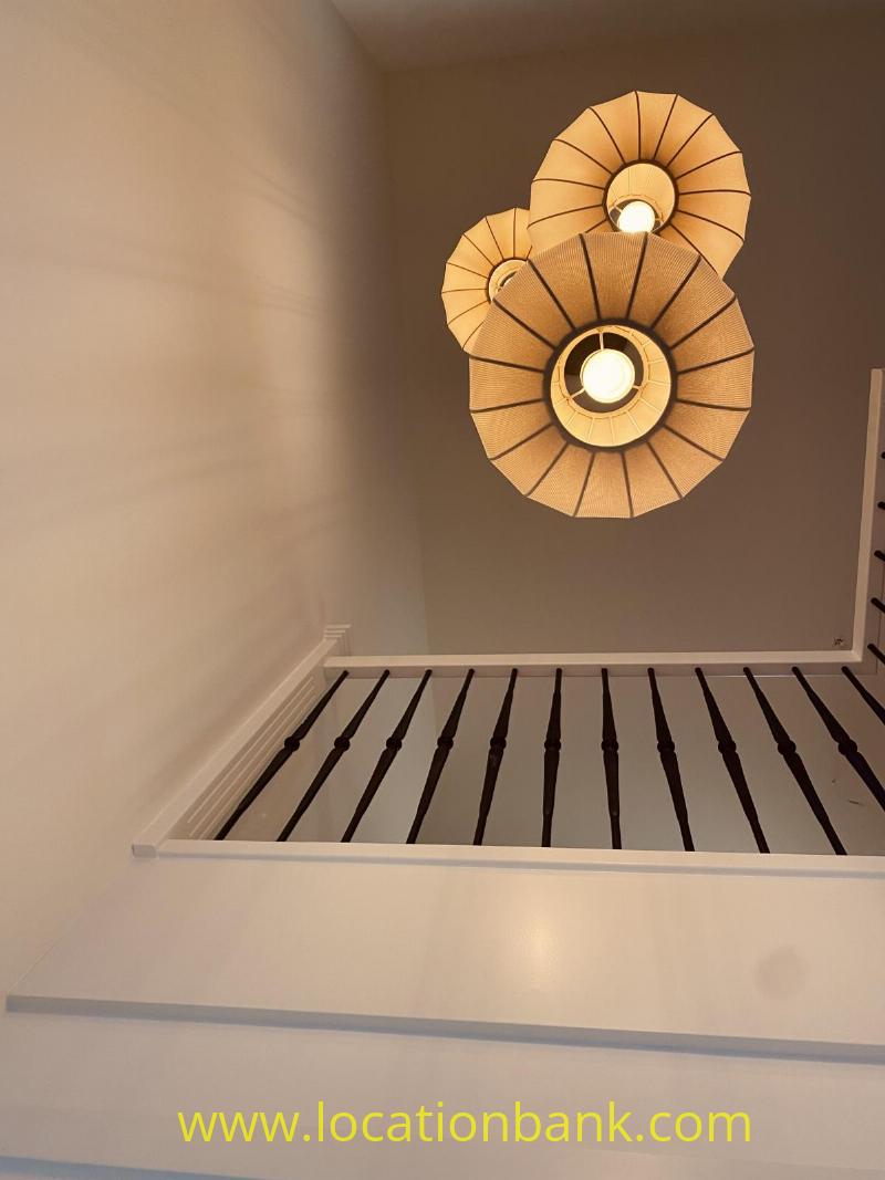 Two overlapping round lampshades with visible ribs and lit bulbs hang above dark vertical slats.