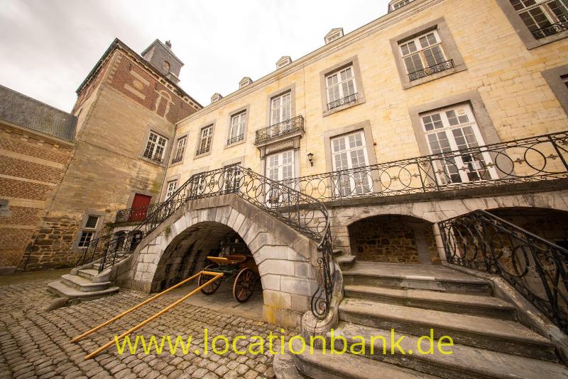 Gebäude aus hellem Stein mit einem Rundbogendurchgang,Stattliche Treppe, verzierten Eisengeländern, einer Kopfsteinpflasterstraße.