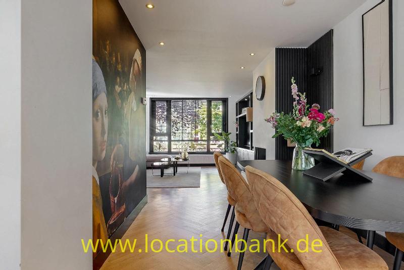Esstisch mit braunen Stühlen, einer Blumenvase und einem großen farbenfrohen Wandgemälde.