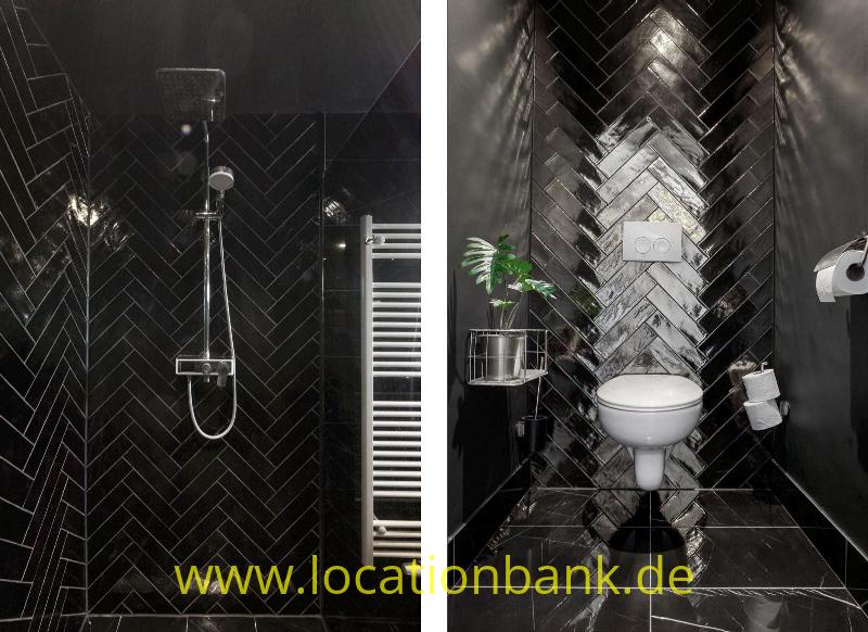 Schwarzes Badezimmer mit Fischgrätfliesen, einer Dusche, einer weißen Toilette und einem weißen Handtuchheizkörper.