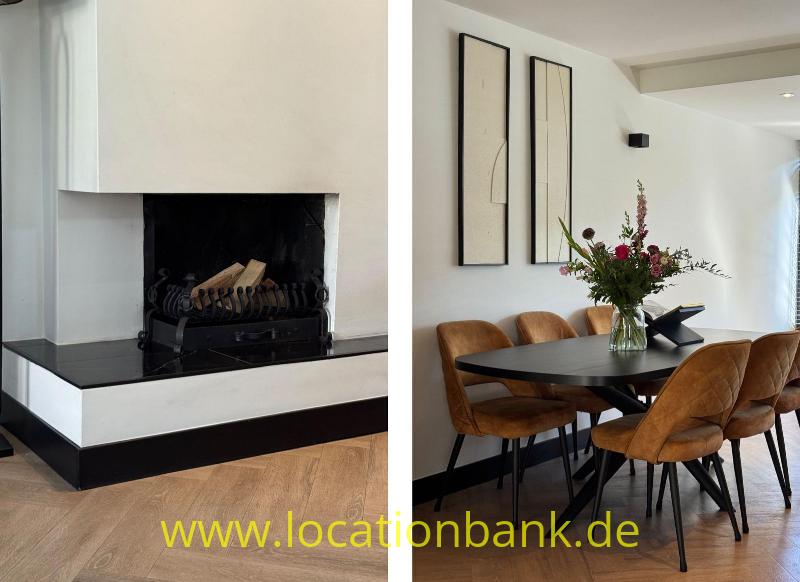 Weißer Kamin neben einem Essbereich mit einem runden Tisch, einer Blumenvase und braunen Stühlen.