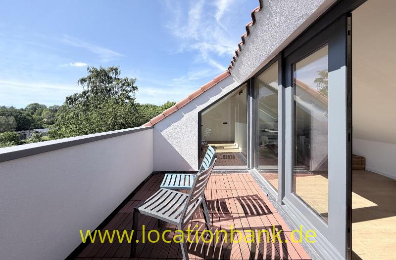 Dachterrasse mit zwei Liegestühlen, Glasschiebetüren und Blick auf Bäume und Hügel.