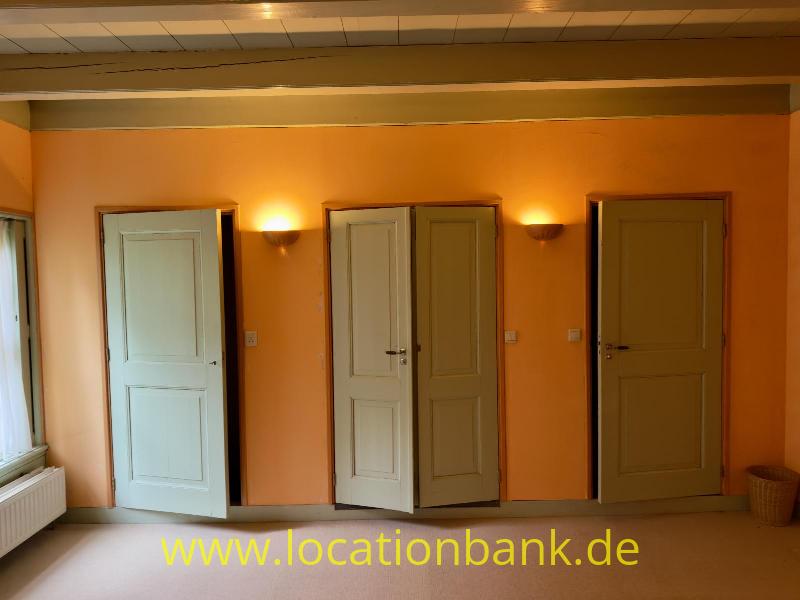 Orangefarbene Zimmerwand mit mehreren hellen Grüne Türen