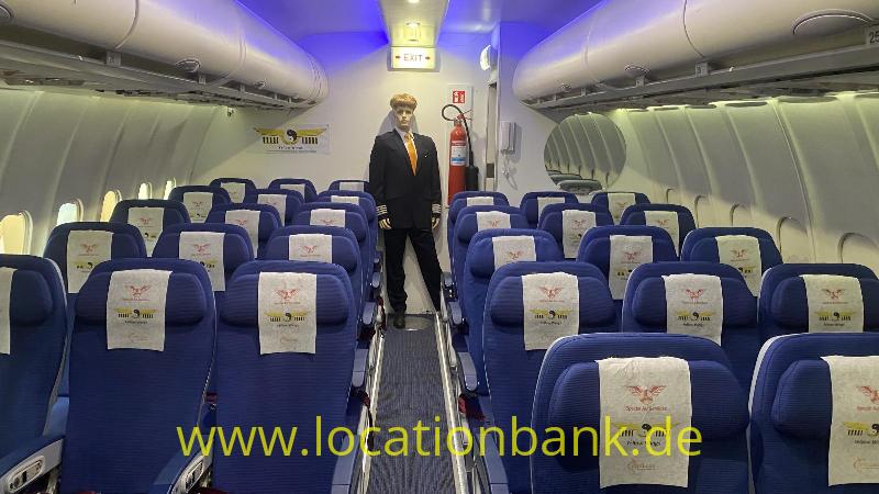 Ein Flugbegleiter steht im Gang zwischen Reihen blauer Sitze im Flugzeug.
