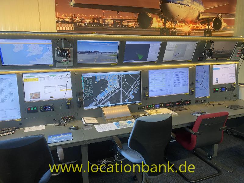Luft Verkehrs Leitung mit mehreren Computerbildschirmen, Bedienfeldern und Bürostühlen unter einem großen Flugzeugbild.