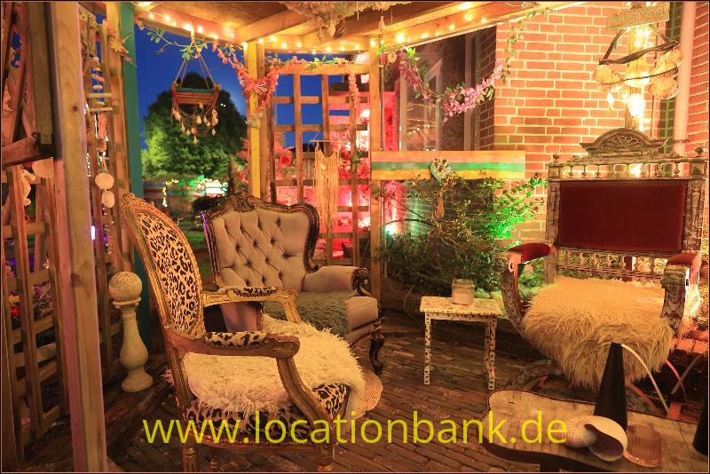 Innenraum mit einem verzierten Sessel, einem geknöpften Sofa, einer Backsteinwand und einem freistehenden Fernseher.