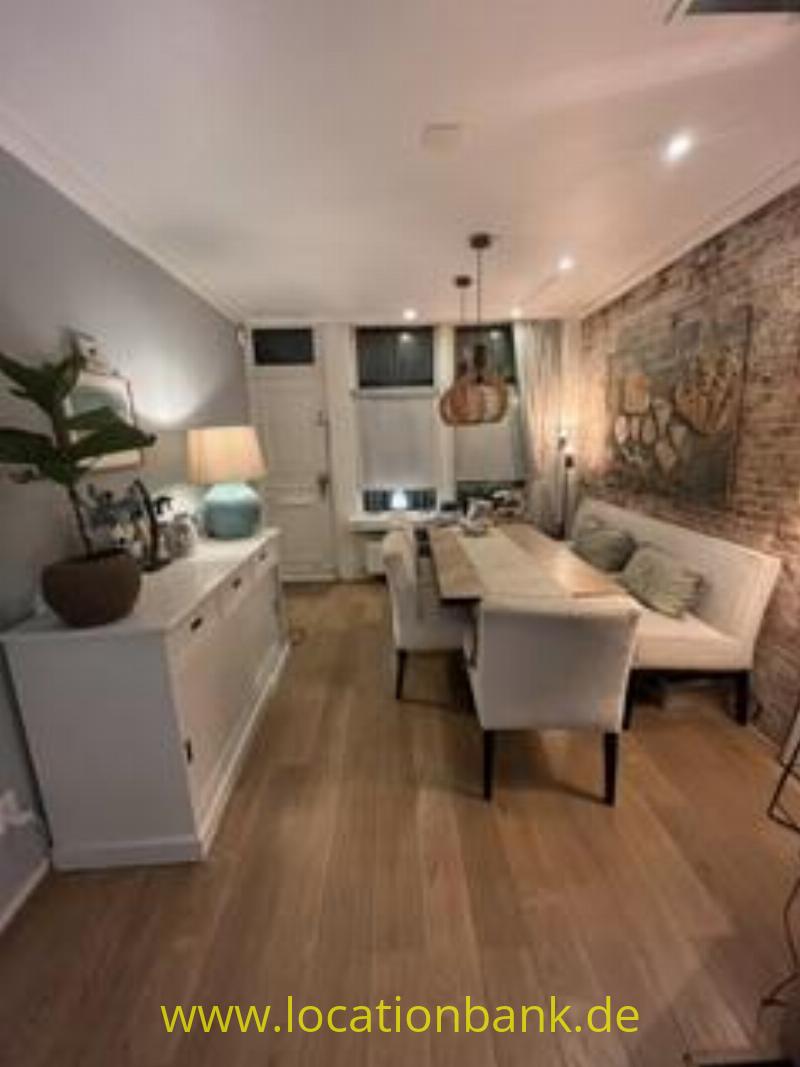 Esszimmer mit einem langen Holztisch, gepolsterten Stühlen und einer Backsteinwand mit einem großen Wandgemälde.