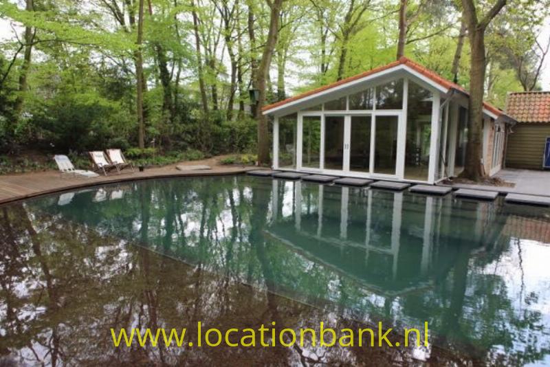 Huis met glas wand aan natuurbad en vijver