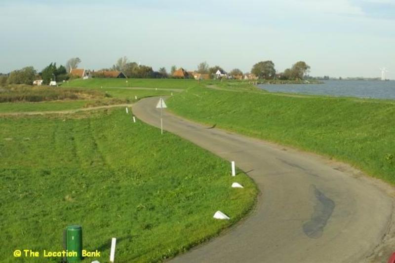 Landweg naast een dijk aan het water