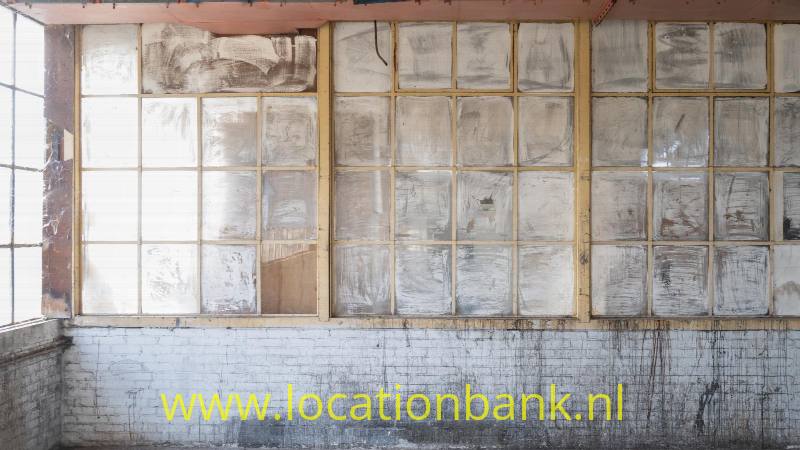 Urbex 1: oude industriële ruimtes op de derde verdieping, met invallend daglicht door grote ramen aan weerszijden van het gebrouw.