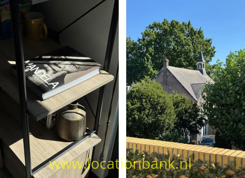 Een open kast met boeken en een mok ernaast een kerkgebouw met torentje, bomen en een bakstenen muur.
