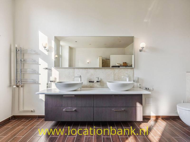 Twee wastafels in badkamer met ronde waskommen boven een lange, moderne wastafelmeubel.