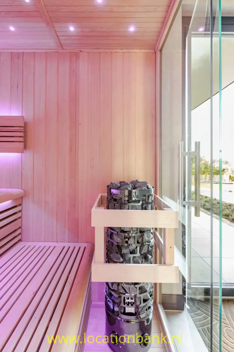 Houten sauna-interieur met banken, een met stenen gevulde saunakachel en een glazen deur.