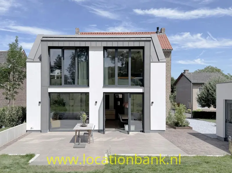 Woninggevel met grote ramen, een rood pannendak en een betegeld terras.