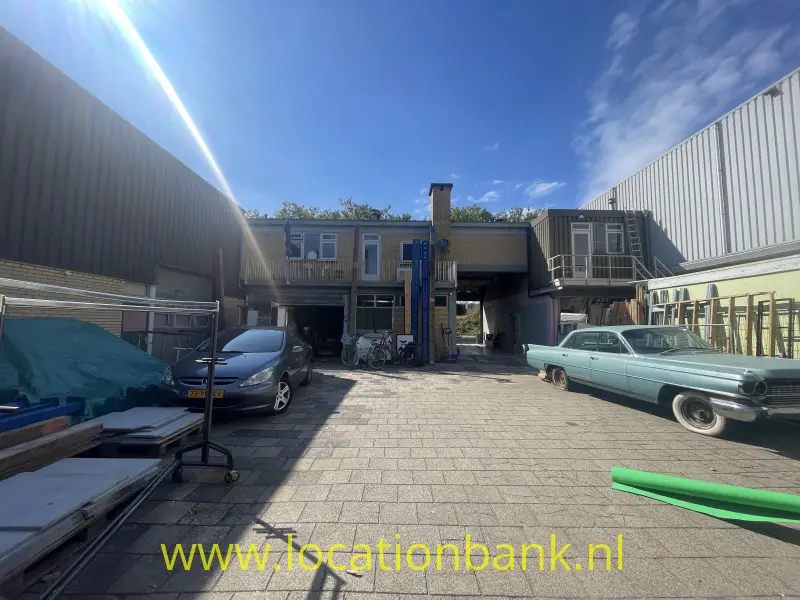 Loodsen en Garage aan Binnenplaats met twee geparkeerde auto’s, een centraal gebouw en hoge metalen gevels 
