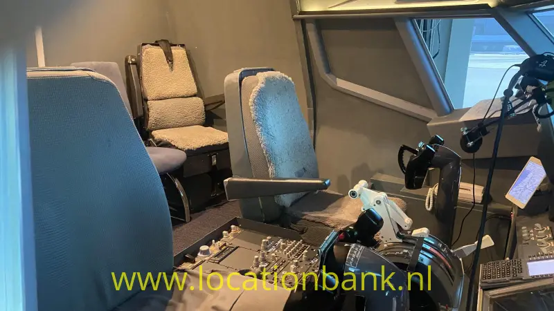 Cockpit met meerdere stoelen, bedieningspanelen, stuurknuppels en grote ramen