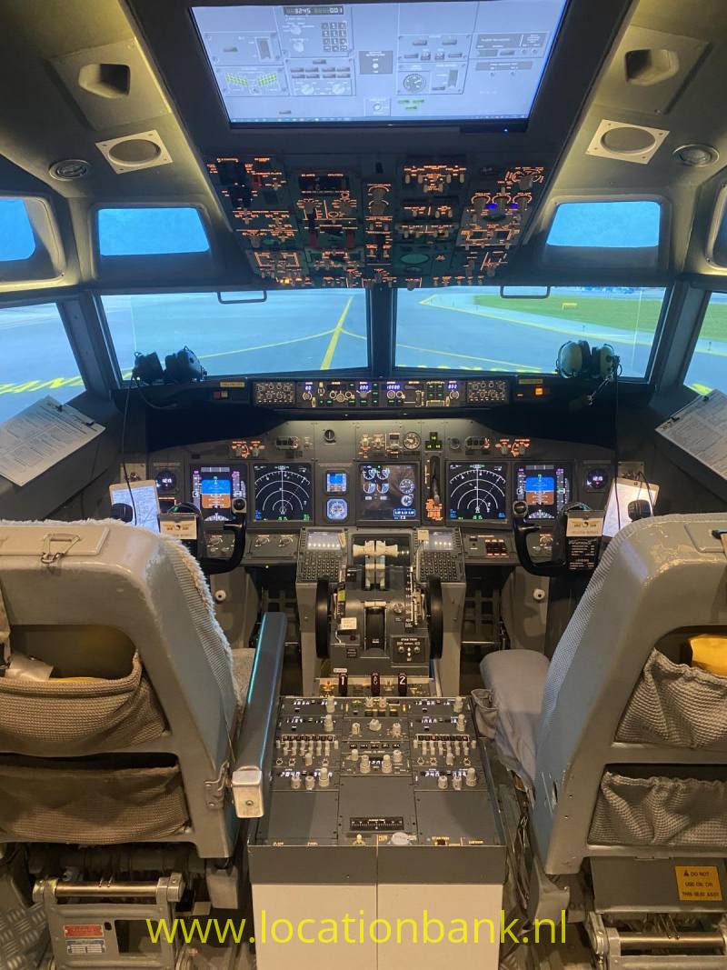 De cockpit toont twee pilotenstoelen, verlichte bedieningspanelen en gele markeringen op de startbaan landingsbaan.