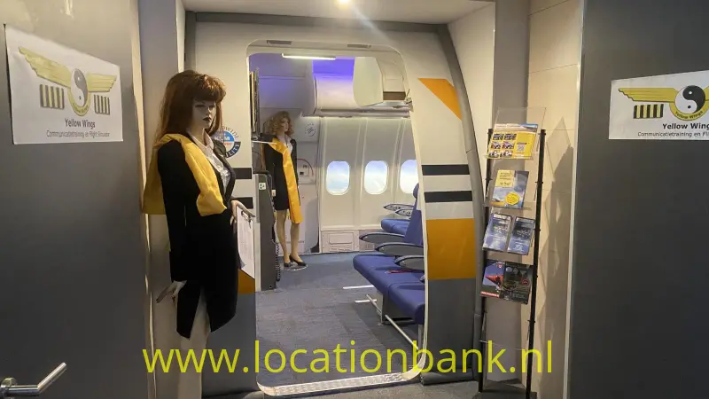 Een open vliegtuigdeur toont blauwe passagiersstoelen, ovale ramen en een stewardess in geel-zwarte kleding.
