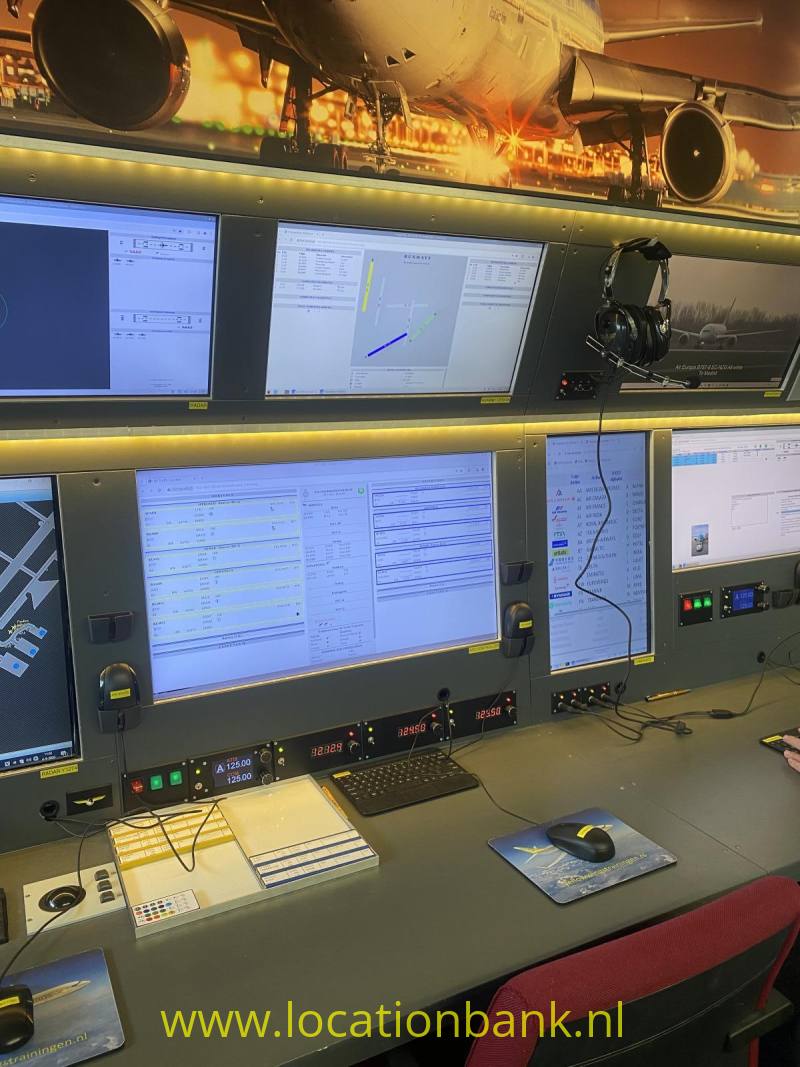 Een bedieningsconsole met meerdere computerschermen, verlichte schakelaars en een rode stoel.