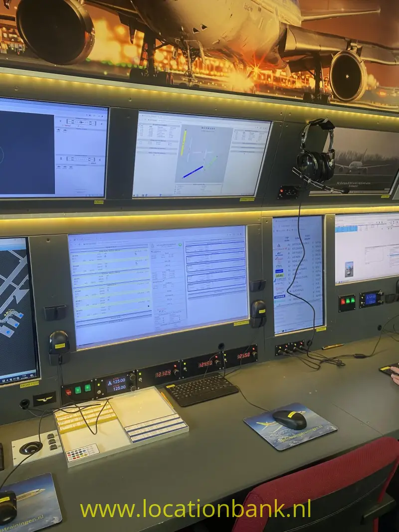 Een bedieningsconsole met meerdere computerschermen, verlichte schakelaars en een rode stoel.