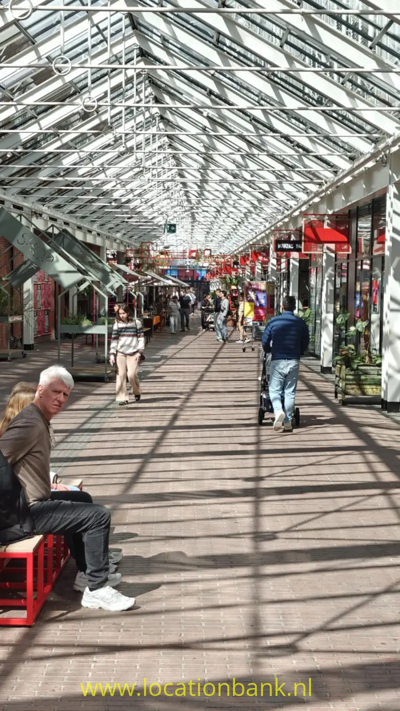 Overdekte passage met glazen dak, winkels, fietsers en voetgangers op een straat vloer.