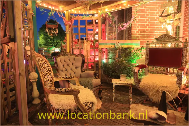 Interieur met een sierlijke fauteuil, een gecapitonneerde bank, een bakstenen muur en een vrijstaande televisie.