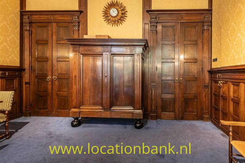Donkere houten kast tussen twee paneeldeuren, met een zonvormige klok erboven.