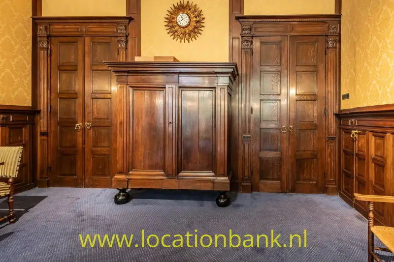 Donkere houten kast tussen twee paneeldeuren, met een zonvormige klok erboven.