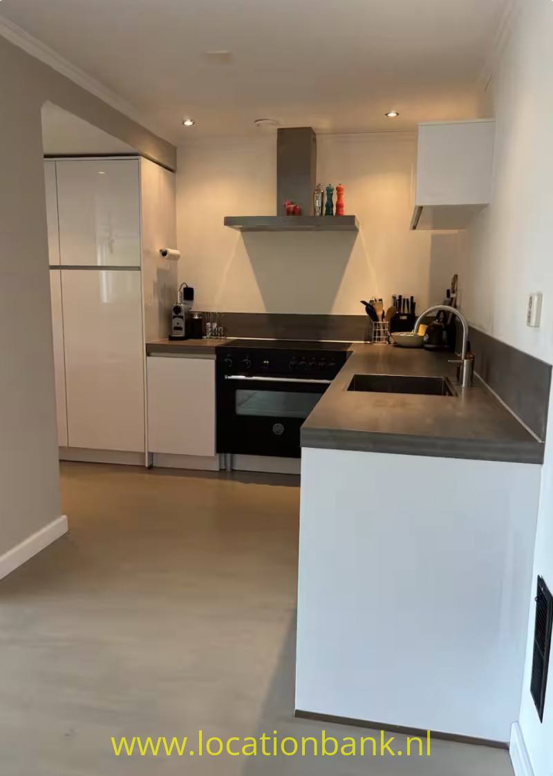 Moderne keuken met kookeiland, ingebouwde oven, inductiekookplaat, spoelbak en witte keukenkasten.