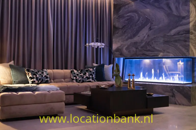 Woonkamer met een hoekbank, donkere gordijnen, een lage salontafel en een lange haard.