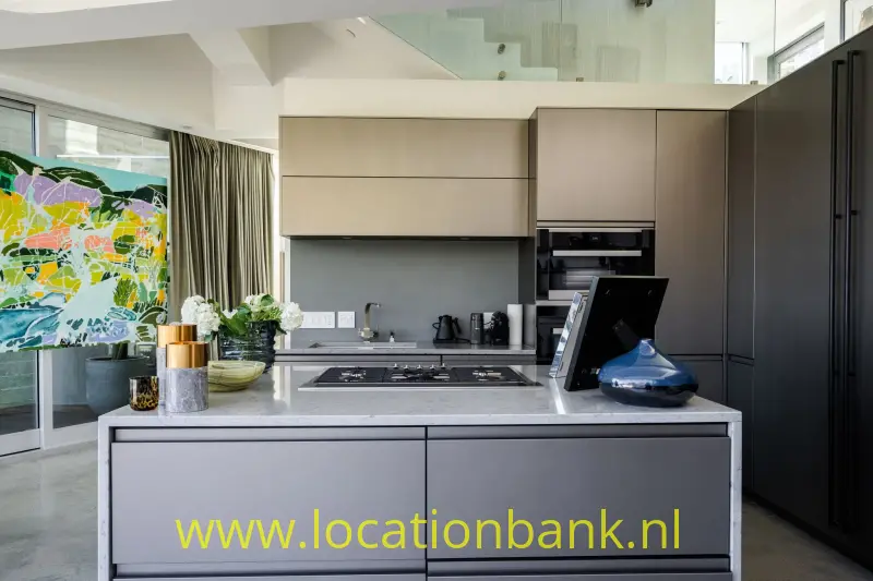 Keuken met een kookeiland, ingebouwde oven, donkere kasten en kleurrijk abstract kunstwerk aan de wand.