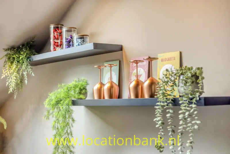 Donkere wandplanken combineren hangplanten met glazen potten en koperkleurige decoratieve objecten.