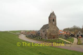 kerk met begraafplaats langs weg en dijk 