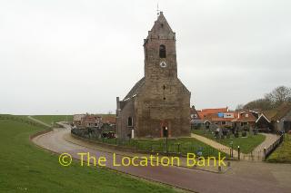 kerk met begraafplaats langs weg en dijk 