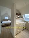 Bedroom beneath a sloping roof with a bed, built-in chest of drawers and a skylight.