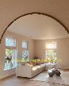 Bright living room with a cream corner sofa, tall windows and a large arched wall mirror.