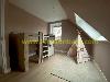 A wooden bunk bed and play tent stand beneath a large skylight in a room with a sloping ceiling.