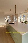 A large kitchen island with pale green cabinets and a white worktop stands at the centre of this kitchen.