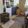 Wood-burning stove with a chimney beside a compact kitchen and a wicker basket in a living space.