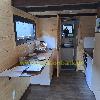 Holzverkleidete Küchenzeile mit Arbeitsfläche, Geschirr und Fenster in einem kleinen Raum.