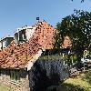 Altes Holz Haus mit steilem roten Ziegeldach, zwei Dachgauben, schwarzer Holzverkleidung 