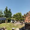 Ein grüner Garten Solarmodule, einen Wäscheständer mit Wäsche und ein rotes Ziegeldach zwischen den Bäumen.