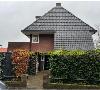 Freistehendes Haus mit großem grauem Ziegeldach, Backsteinfassade, Vorgarten und überdachtem Eingang.